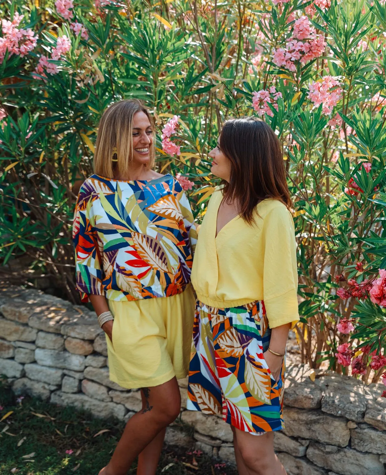 short fleuri haut jaune duo sourire devant des lauriers vue de face