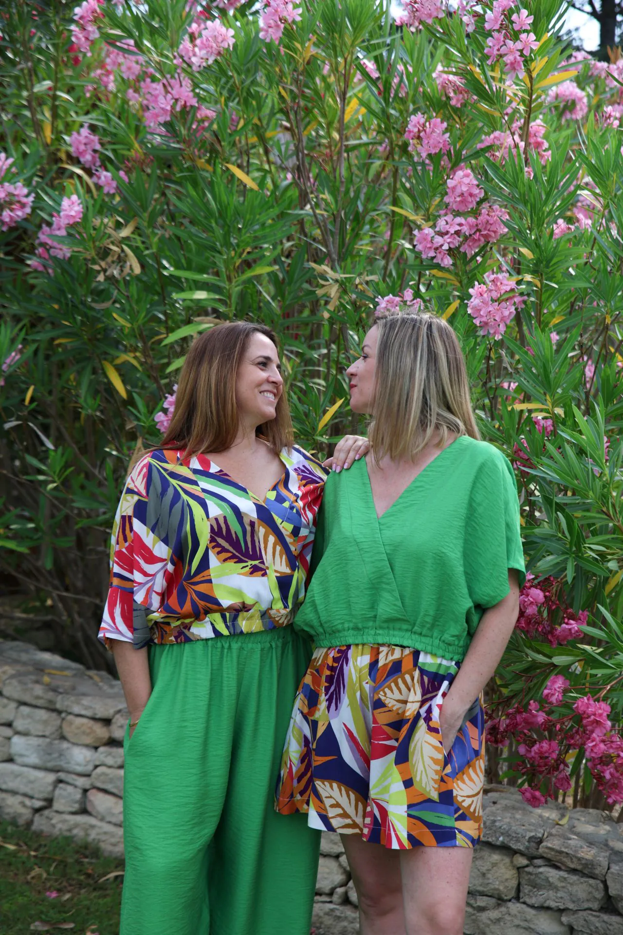 duo haut vert et short fleuri sourire vue de face derriere lauriers